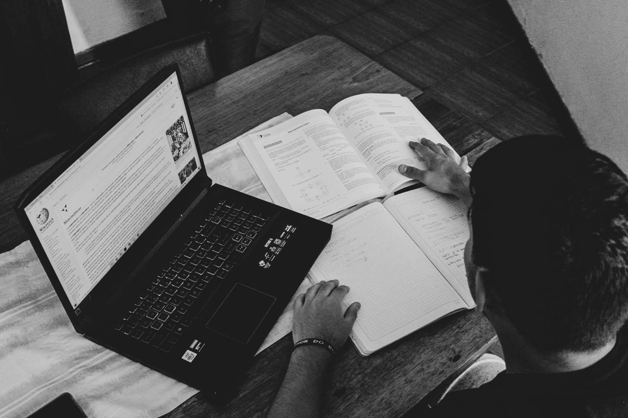 An overhead view of someone researching with a laptop and open book