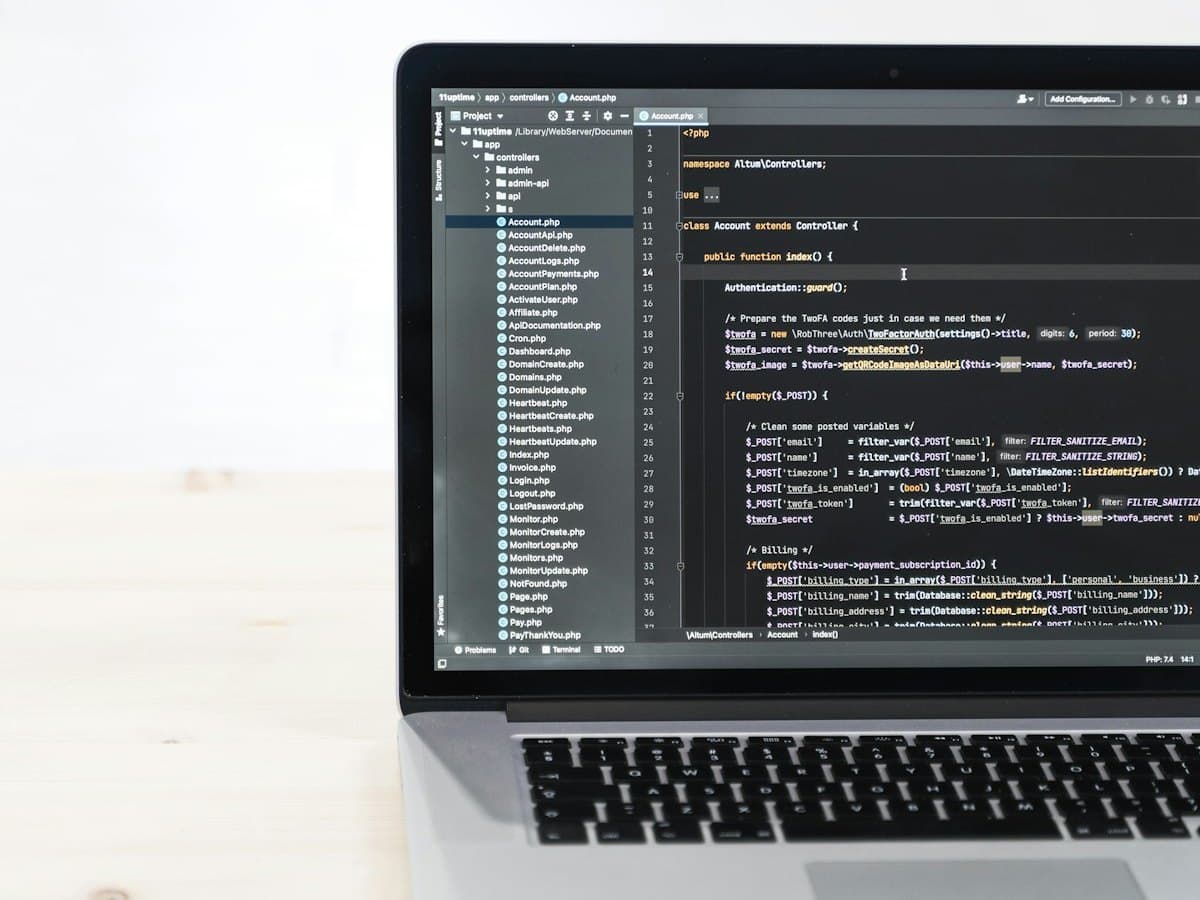 A laptop open on a code editor, on a pale wooden desk